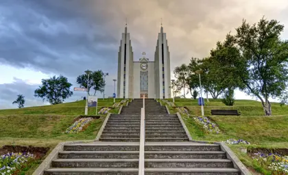 Akureyri Church at sunset with a grand staircase and flower beds on a hilltop in North Iceland