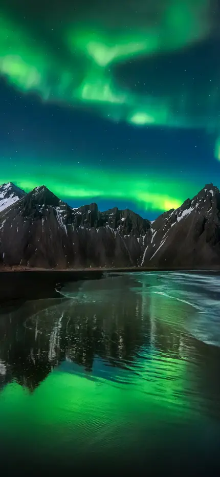 Northern Lights shining brightly over Vestrahorn mountain in Iceland, featured as a banner for Travel Reykjavik's tour promotions.