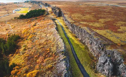 Aerial view of the tectonic rift valley at Þingvellir National Park in Iceland, where the North American and Eurasian plates meet, surrounded by autumn-colored landscape.