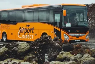 Orange Airport Direct Grayline Airport bus driving through Reykjanes lava field.