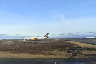  Airplane Arriving in Iceland on the ground at Keflavik Airport under a blue sky.