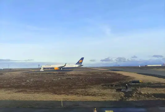  Airplane Arriving in Iceland on the ground at Keflavik Airport under a blue sky.