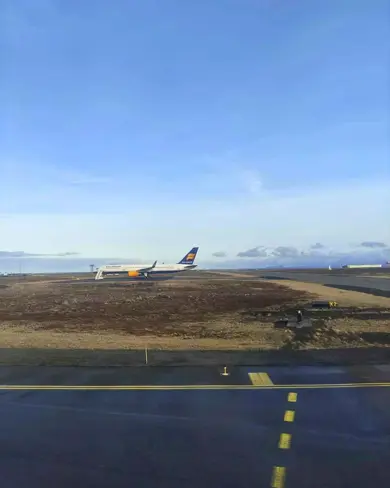  Airplane Arriving in Iceland on the ground at Keflavik Airport under a blue sky.