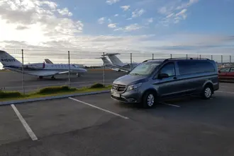 Private Airport Shuttle van outside airport in Iceland with planes in the background.