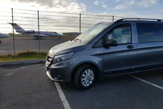 Private Airport Shuttle vehicle parked with airplanes in the background.