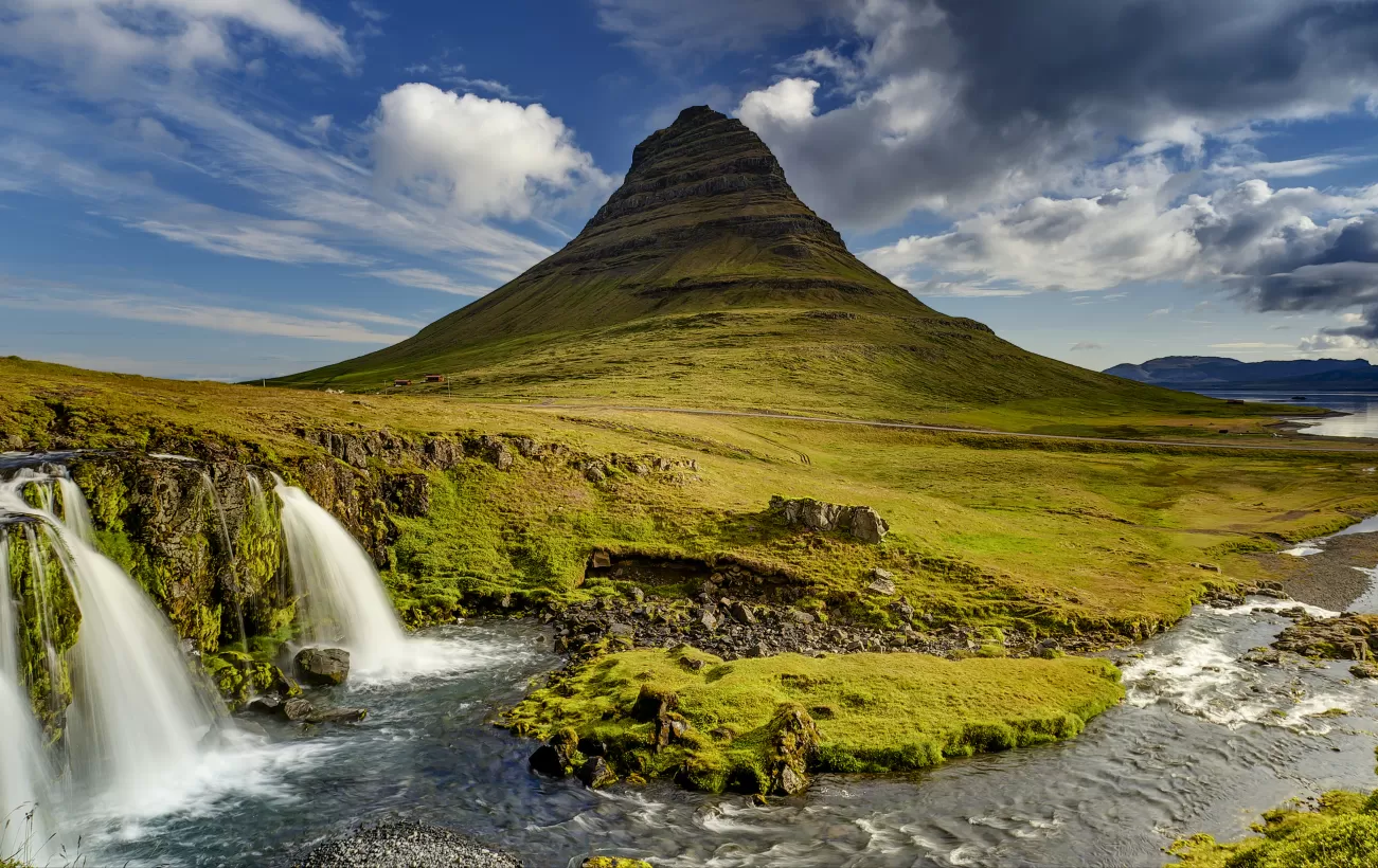 Kirkjufell Mountain and waterfall under a blue sky in Iceland.