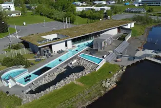 Aerial view of Fontana geothermal spa in Iceland, with outdoor pools surrounded by greenery and modern architecture, offering a unique relaxation experience.