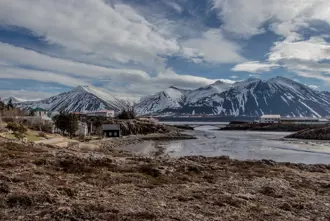 Borgarnes town with snow-capped mountains in the background, a picturesque coastal view highlighting Iceland's natural beauty.