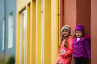 Two Little Girls Next To A Colorful House In Reykjavik Iceland Large