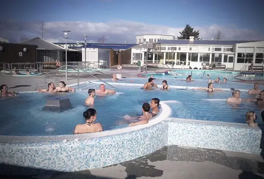 Vesturbaejarlaug swimming pool hot tub area with people relaxing.