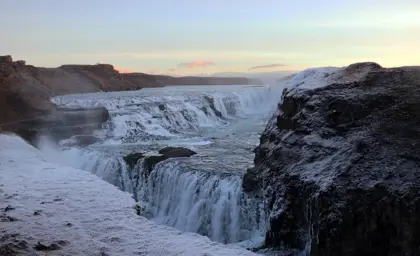 A panoramic view of Gullfoss waterfall in winter, covered with snow and ice, located along the Golden Circle in Iceland.