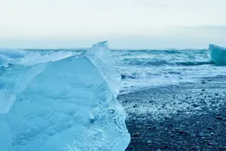 Diamond beach black sand beach in winter with icebergs on the sand and waves coming in.
