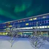 Berjaya Reykjavík Natura Hotel exterior view under the northern lights in the winter sky.
