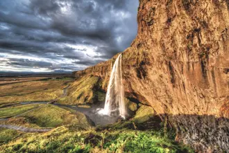 Seljalandsfoss Waterfall With Vast Fields In Background And Dark Stormy Sky Large