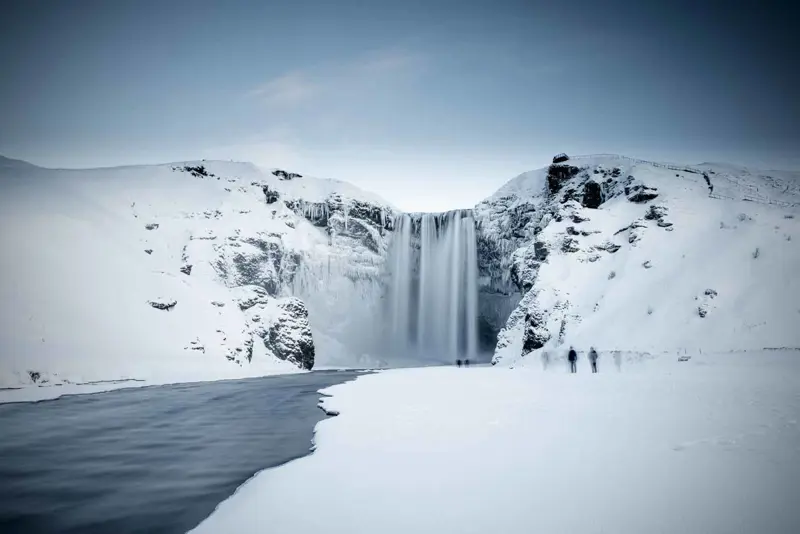The majestic Skogafoss waterfall covered in snow and ice during winter in Iceland, creating a serene and powerful scene.