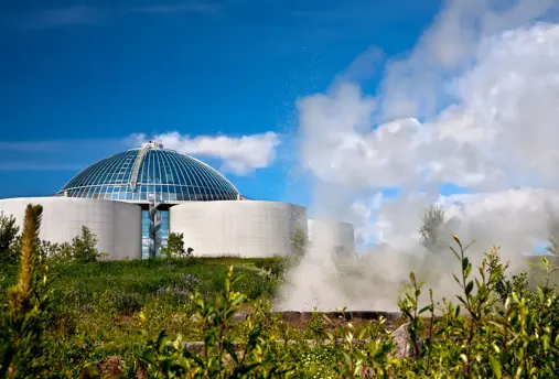 View of Perlan Museum and observation deck through a steam cloud and greenery.