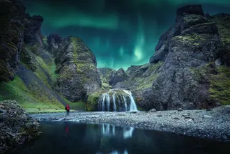 Northern Lights above hidden waterfall in a canyon in Iceland.