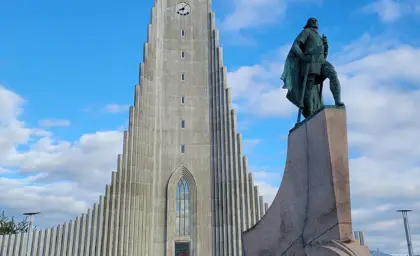 Statue of Leif Erikson in front of Hallgrímskirkja church under a bright blue sky in Reykjavík, Iceland, a popular attraction on city tours.