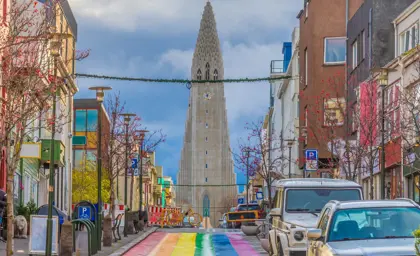 View of Skólavörðustígur street with its vibrant rainbow-painted pavement leading to Hallgrímskirkja church in Reykjavik, Iceland, showcasing the city's colorful and inclusive spirit.