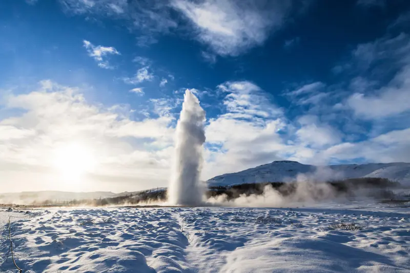 Eruption of Geysir hot spring in Iceland on a clear blue day, showcasing the natural geothermal beauty of the Golden Circle.