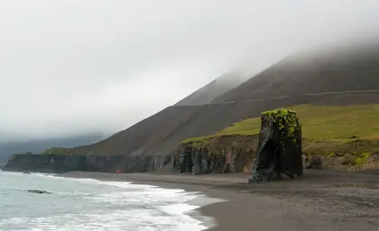 Foggy morning at Fauskasandur Black Sand Beach with towering cliffs and misty coastline in East Iceland