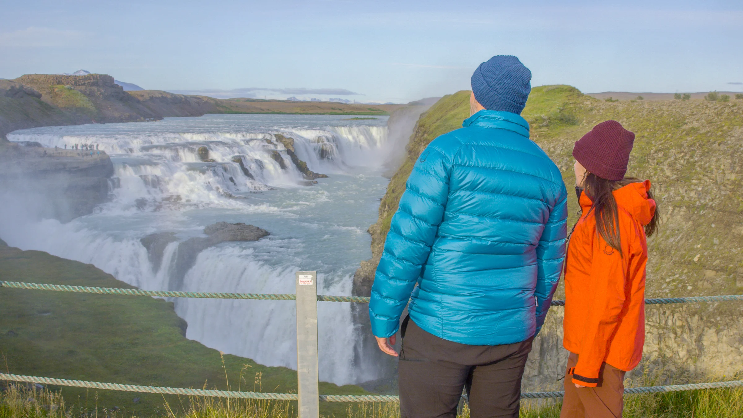 Two people view Gullfoss from the waterfall's lookout point.