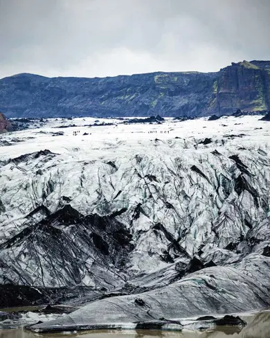 The dramatic landscape of Mýrdalsjökull glacier in Iceland with hikers on the glacier.