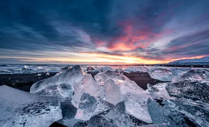Sunrise at Fellsfjara Diamond Beach with icebergs glistening on the black sand, showcasing Iceland's stunning natural beauty.