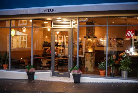 A warm and inviting view of Vedur Cafe in Reykjavik, Iceland, featuring its cozy interior and glowing ambiance, perfect for a relaxed dining or coffee experience.