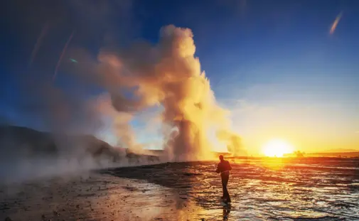 Person in front of a geyser during sunset on a private golden circle tour in Iceland.
