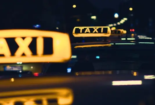 Top of taxis with yellow signs glowing in the dark night. 