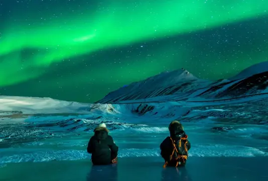 Sitting On Frozen Lake Watching Northern Lights Iceland.