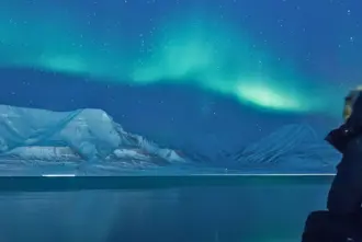Sitting Watching Northern Lights Over Mountains Iceland.