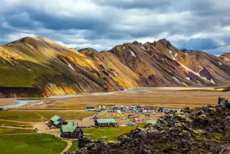 Campsite at Landmannalaugar in Iceland's Highlands, with colorful tents and cabins set against rugged rhyolite mountains.