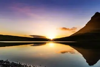 Midnight Sun in Iceland shining over Kirkjufell Mountain and lake on Snæfellsnes peninsula.