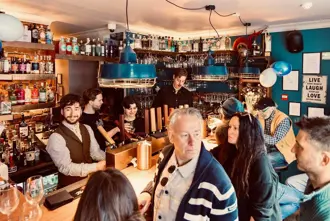 Interior of Kaldi Craft Bar in Reykjavik, capturing patrons enjoying drinks in a cozy, warmly-lit setting with an extensive selection of spirits and beers.