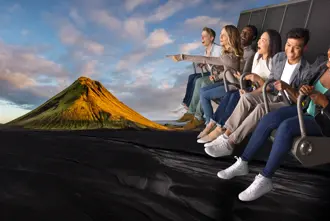 Enthusiastic group on FlyOver Iceland ride, suspended over a scenic Icelandic mountain landscape.
