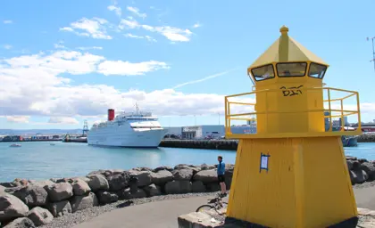 Reykjavík Harbor view of small yellow lighthouse and cruise ship in background.
