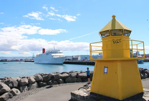 Reykjavík Harbor view of small yellow lighthouse and cruise ship in background.
