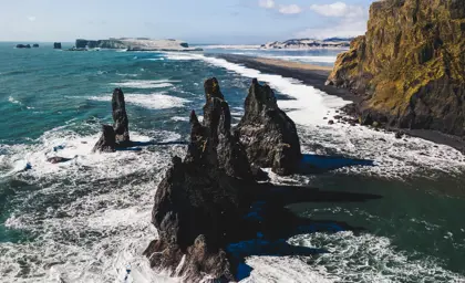 Reynisdrangar basalt sea stacks rising from the ocean near Reynisfjara Black Sand Beach on Iceland's South Coast, a popular sight on travel tours.
