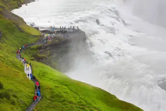 West side of Gullfoss waterfall with visitors walking along the path close to the falls.