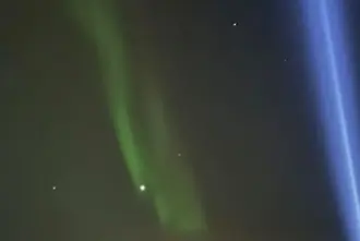 Northern Lights from Videy island with Imagine Peace Tower blue light shining in the sky next to the auroras.