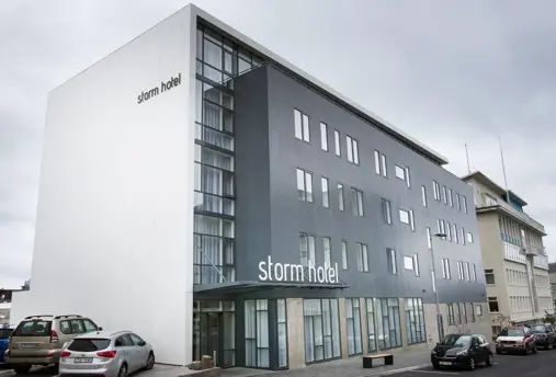 Exterior of Storm Hotel in Reykjavík with modern grey and white façade and parked cars.