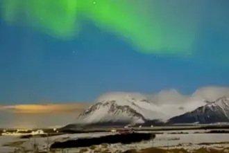 Borgarnes Iceland with Northern Lights above snowy mountains.