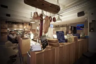 Interior of Slippbarinn bar in Reykjavik, featuring rustic wood decor and hanging cured meats.