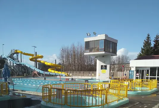 Outdoor view of Breiðholtslaug swimming pool in Reykjavík, showcasing water slides and family-friendly facilities under a bright, sunny sky.