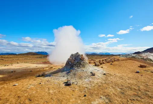 Námaskarð Geothermal Area with steam rising up to a blue clear sky.