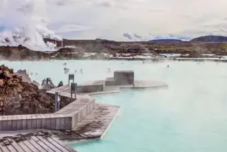 The geothermal pool area of the Blue Lagoon in Iceland with wooden walk ways around lava rocks.