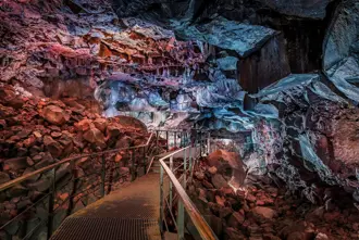 Views inside Raufarhólshellir lava tunnel cave in Iceland with walking path going through the cave.