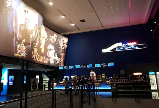 Interior of Sambíóin Egilshöll cinema in Reykjavik, featuring vibrant movie posters, a snack counter, and a modern cinematic ambiance.